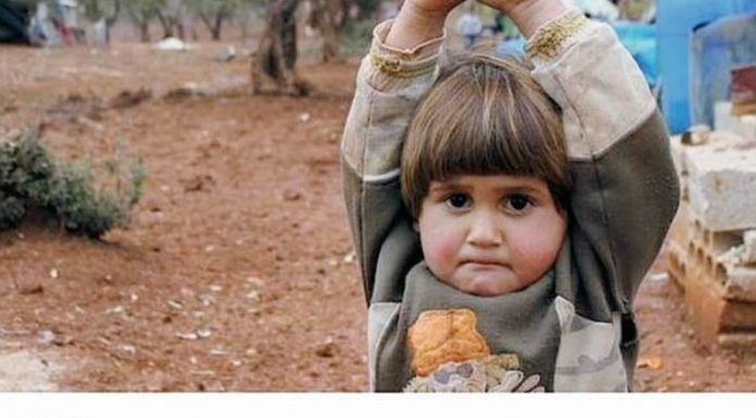 Una niña siria levanta las manos al confundir una cámara con un arma